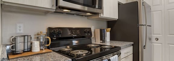 A kitchen with a black stove top oven and a black microwave above it.