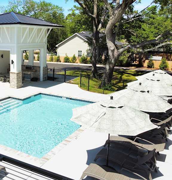 A pool with a black railing and a white umbrella.
