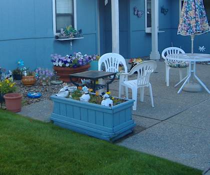 Image of outdoor patio space with tables, chairs, plants and umbrella