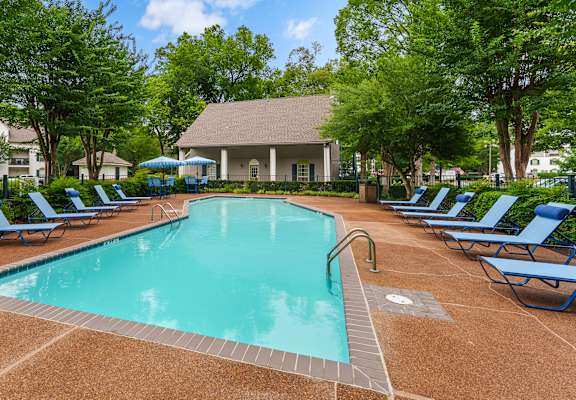 A large swimming pool surrounded by blue lounge chairs.