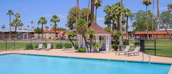 a swimming pool with chaise lounge chairs and palm trees in the background