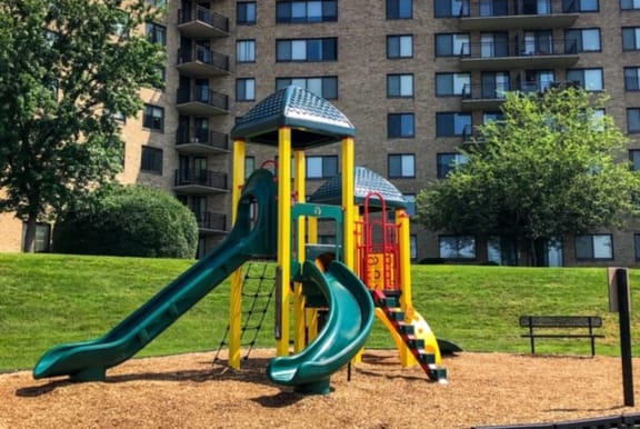 a playground with slides in front of an apartment building