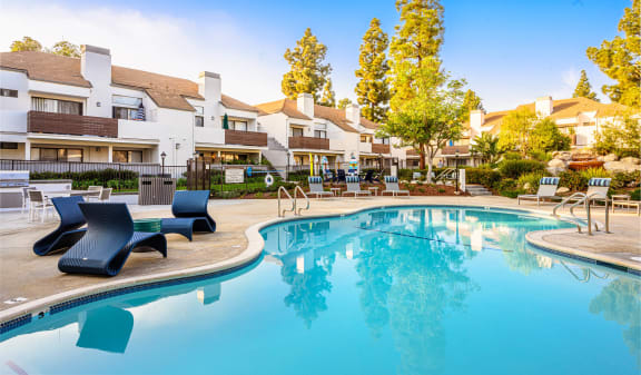 a swimming pool with lounge chairs and buildings in the background at Sendero Huntington Beach, Huntington Beach