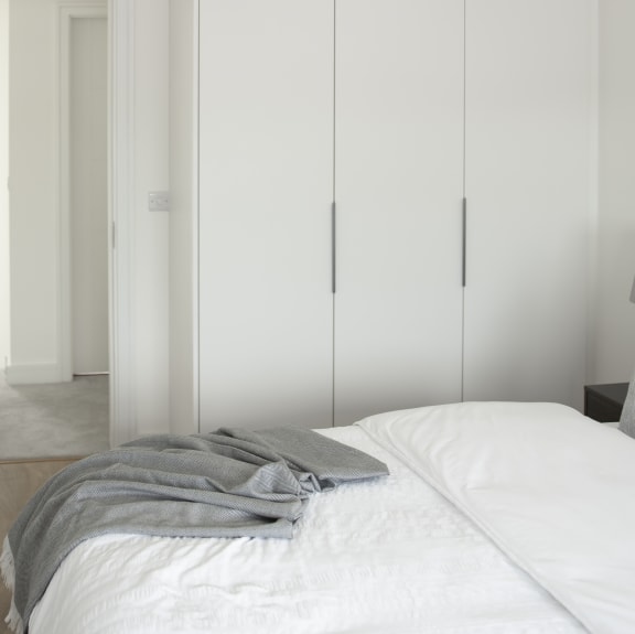 a bedroom with white closet doors and a white bed