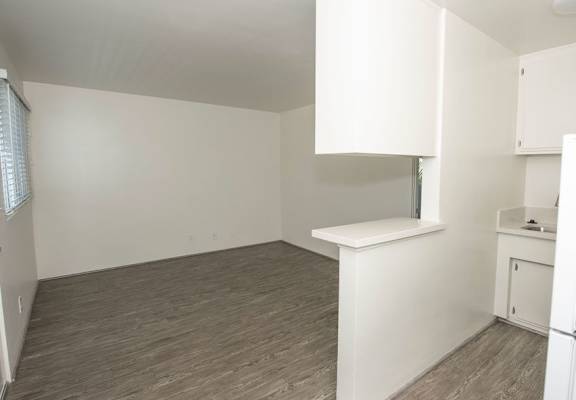 A kitchen area with a refrigerator, sink, and cabinets.