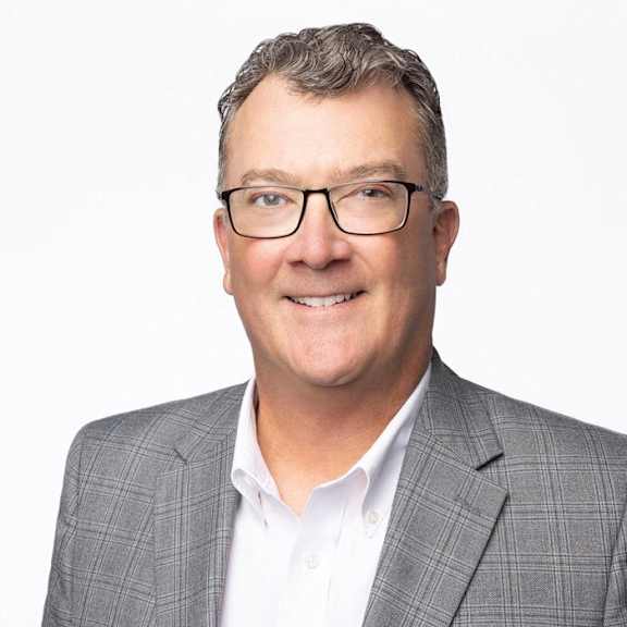 a man in a suit and glasses smiling