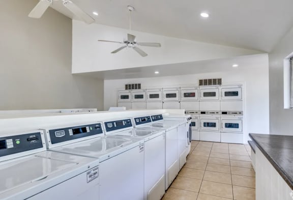 A row of white washing machines are lined up in a laundry room.