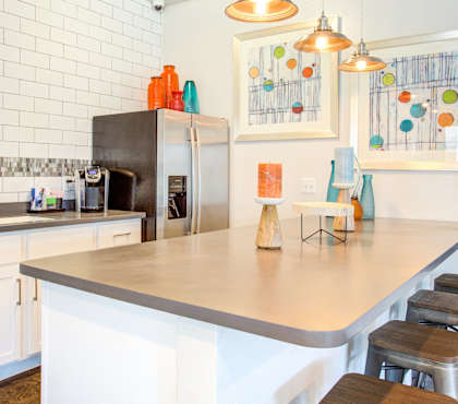 A kitchen with a white counter top and a black refrigerator.