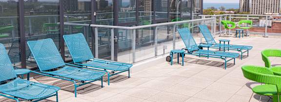 A patio with blue and green chairs and tables.