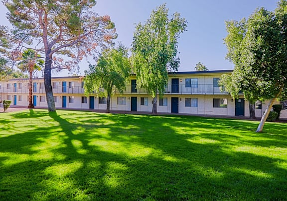 A grassy area in front of a building with trees.