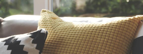 a couch with pillows and a fur throw in front of a window