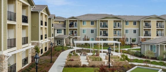 an exterior view of an apartment complex with a green courtyard
