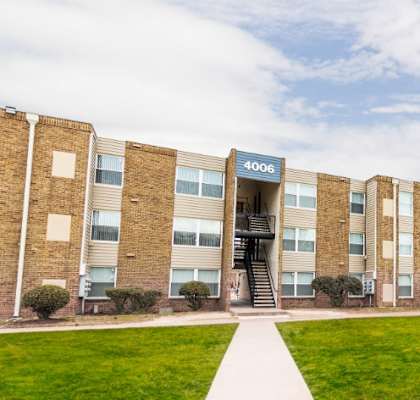 a row of brick buildings with a green lawn in front of them at The Belt Atlantic Apartments, Richmond, VA, 23224