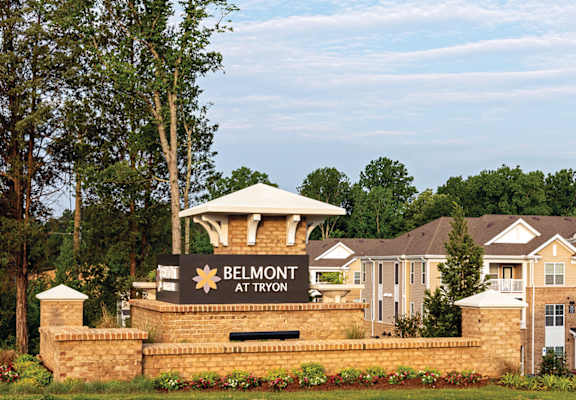 Community entrance with brick sign; apartment buildings