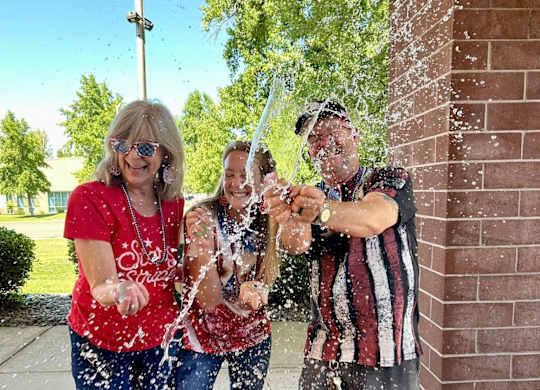 Three people are playing with water at River Commons Senior Living, California