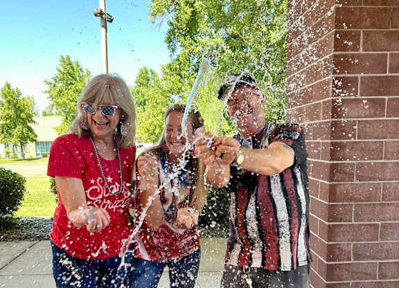 Three people are playing with water at River Commons Senior Living, California