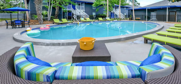 Mandarin Bay apartments with pool in Jax, 32257 with lime green loungers and a large green and blue striped patio couch with table.