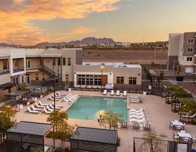 a building with a pool in the desert at sunset