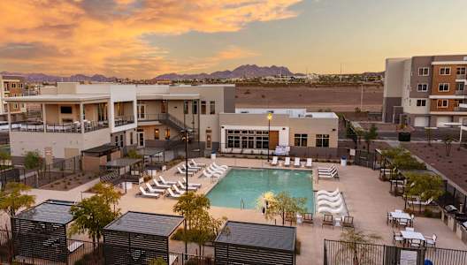 a building with a pool in the desert at sunset