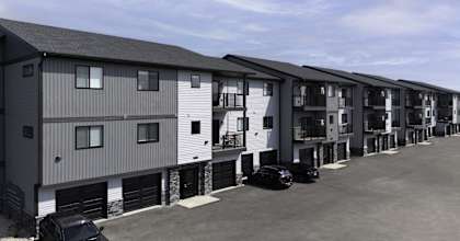 a row of apartment buildings with cars parked in front