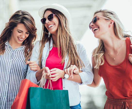 three women walking down the street with shopping bags at The Station at River Crossing, Macon, GA