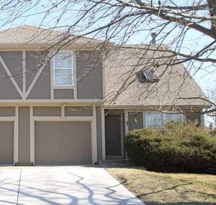 a house with two garage doors and a sidewalk in front of it