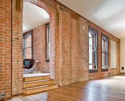 an empty room with a wood floor and brick walls