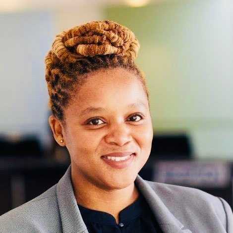 A woman with braided hair wearing a grey blazer and black shirt.