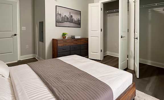 A bedroom with a bed, dresser, and a painting on the wall.