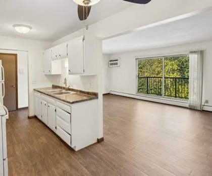 A white kitchen with a wood floor and a ceiling fan.