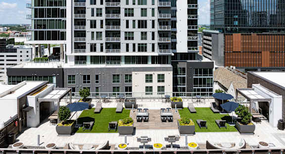 a roof top patio with tables and chairs and grass