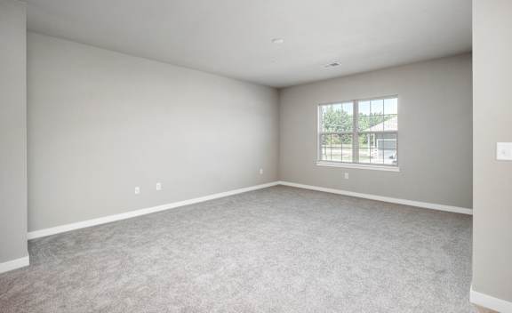 Empty room with a window and carpeted floor.