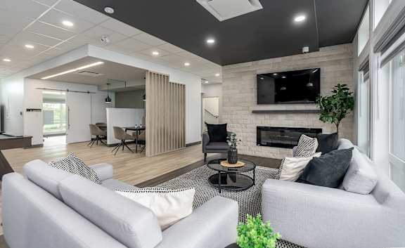 A modern living room with a grey sofa, a black coffee table, and a fireplace with a TV above it.