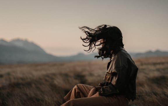 a woman sitting on a rock in a field