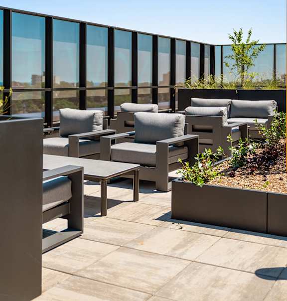 A patio with grey cushioned chairs and tables.