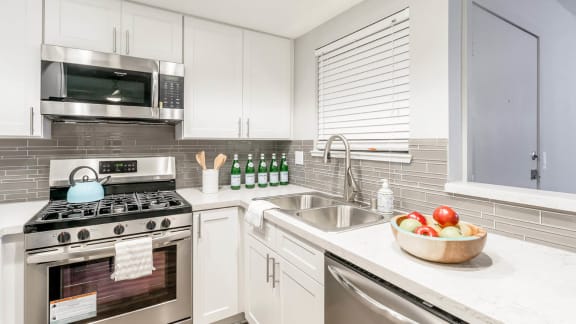 a modern kitchen with stainless steel appliances and white cabinets