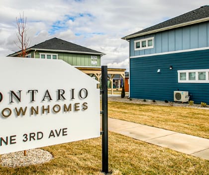 A sign for Ontario Townhomes stands in front of a building.