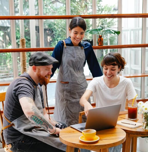 a group of people sitting around a table looking at a laptop
