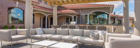 a patio with white couches and a wooden pergola