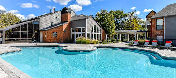 A large swimming pool in front of a building with a glass wall.