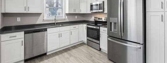 a white kitchen with black counter tops and white cabinets