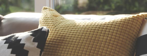 a couch with pillows and a fur throw in front of a window