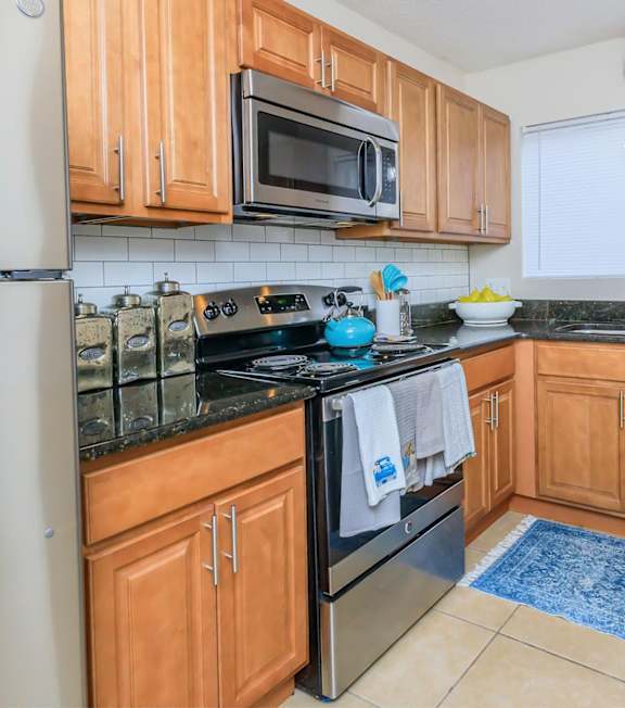 A kitchen with wooden cabinets and black countertops.