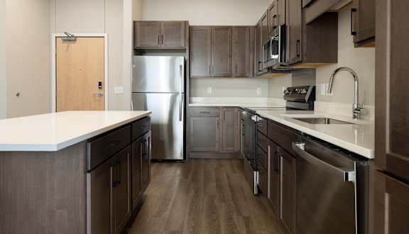 A modern kitchen with dark wood cabinets and stainless steel appliances.