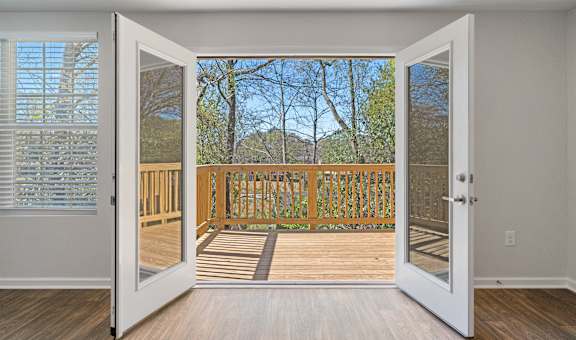 an open door leading to a balcony with a view of the woods