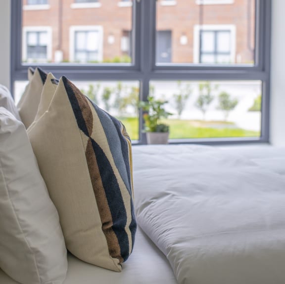 a bed with pillows in front of a window