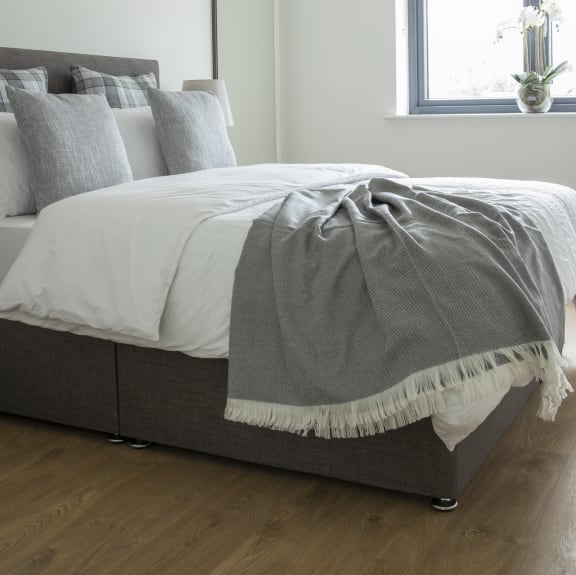 a bedroom with a bed with white sheets and pillows and a window