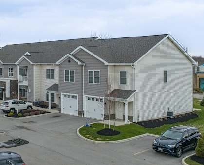 A parking lot in front of a building with cars parked.