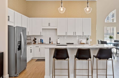 a kitchen with white cabinets and a counter top with three stools at Parkway Trails, Florence, KY, 41042