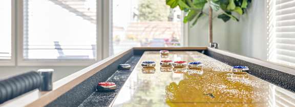 A shuffleboard table in the middle of a well-furnished room.